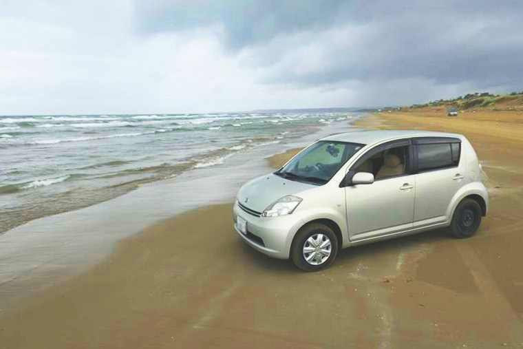 千里浜なぎさドライブウェイ 波打ち際に車を停めて記念撮影