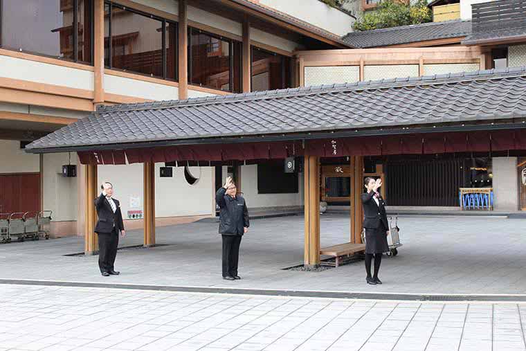 送迎バスが見えなくなるまで手を振る従業員