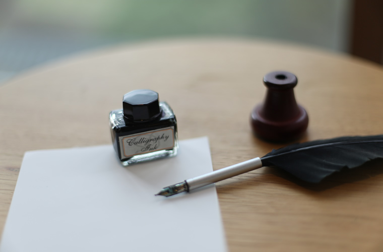 窓際にさりげなく置かれた羽ペンとメモ紙