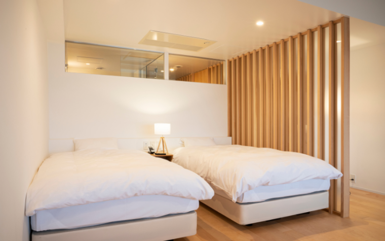 815号室の「AKARI（あかり）」。ツインベッドが完備され、部屋のバスルームでも温泉を楽しめます