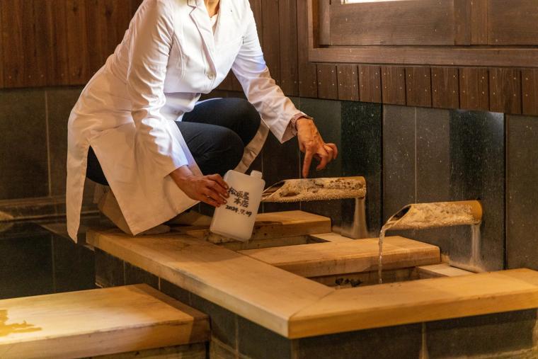 大浴場の浴槽流入口より採水している様子